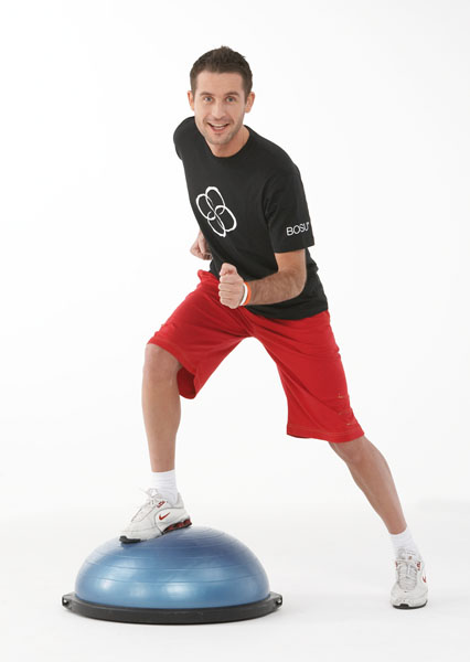 Trainer trabaja con una bola de equilibrio (bosu) en el gimnasio